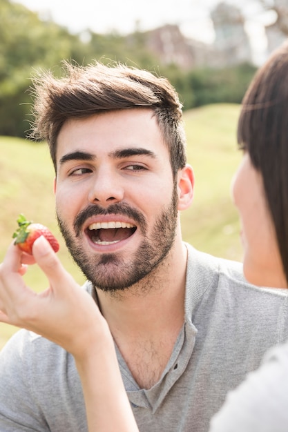 Woman feeding fresh strawberry to her boyfriend