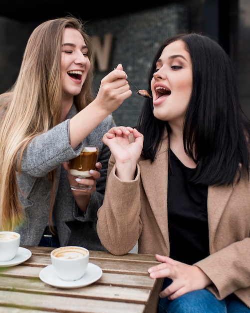 Woman feeding her friend with her dessert