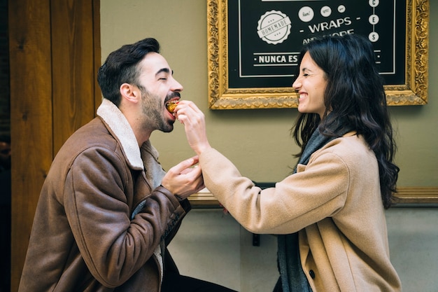 Woman feeding man in outdoor cafe