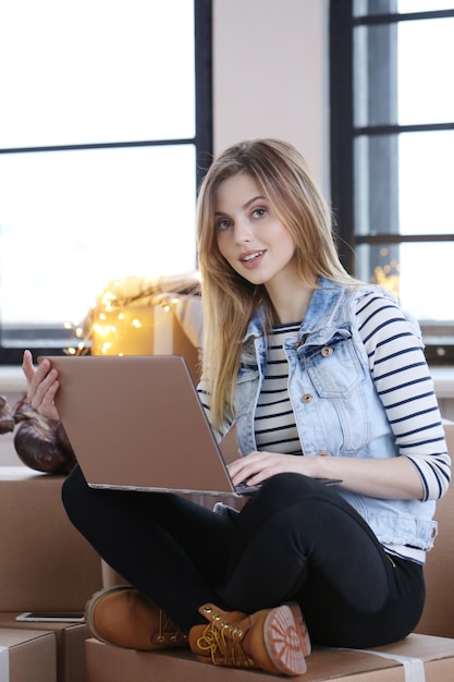 Free photo woman finished with cargo packages and is calling a courrier for shipping via computer