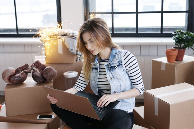 Woman finished with cargo packages and is calling a courrier for shipping via computer