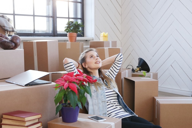 Woman finished with cargo packages and is sitting on the floor in a satisfied manner