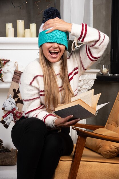 Foto gratuita donna che ripara il suo cappello mentre tiene il libro.