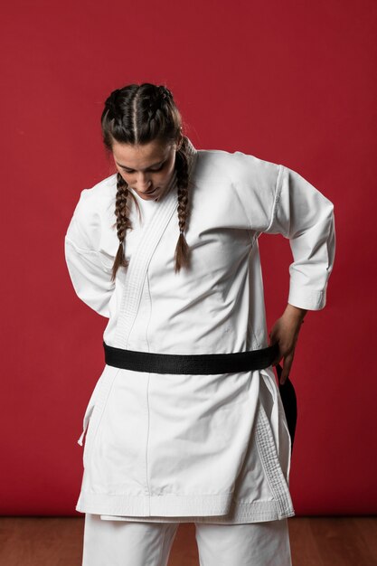 Woman fixing her karate kimono and looking down