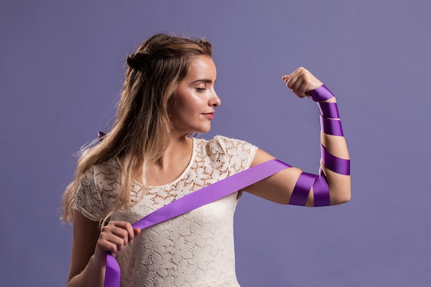 Free photo woman flexing her arm with ribbon as a sign of empowerment