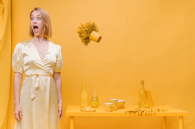 Free photo woman and floating flower pot in a yellow scene