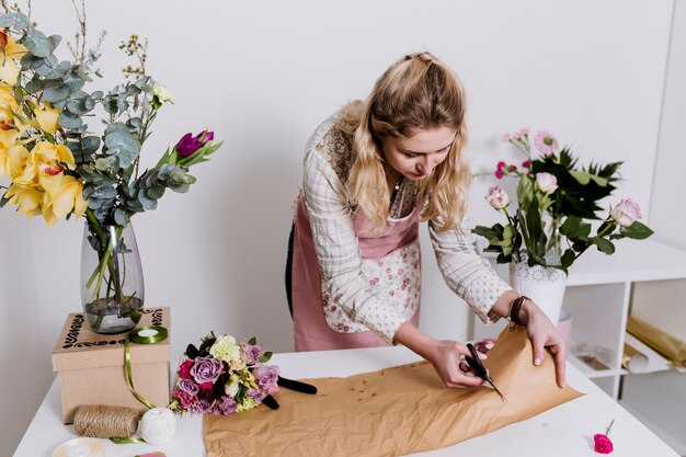 Woman florist cutting paper for flowers