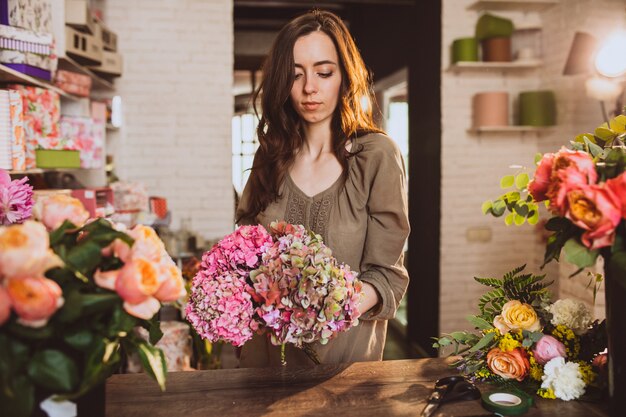 Woman florist at her own floral shop taking care of flowers