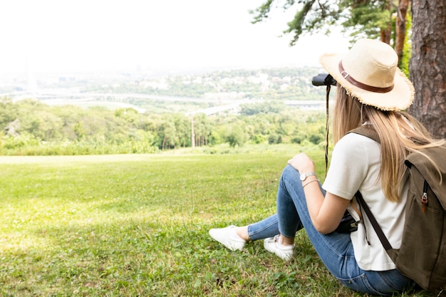 Foto gratuita donna in foresta che osserva tramite il binocolo