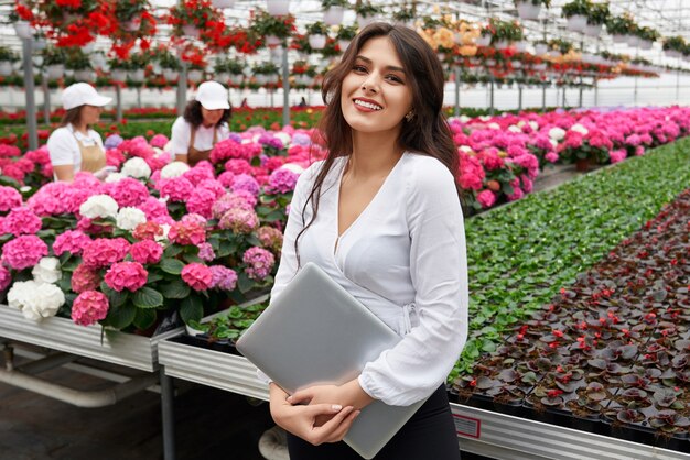 Woman in formal wear holding laptop at greenhouse