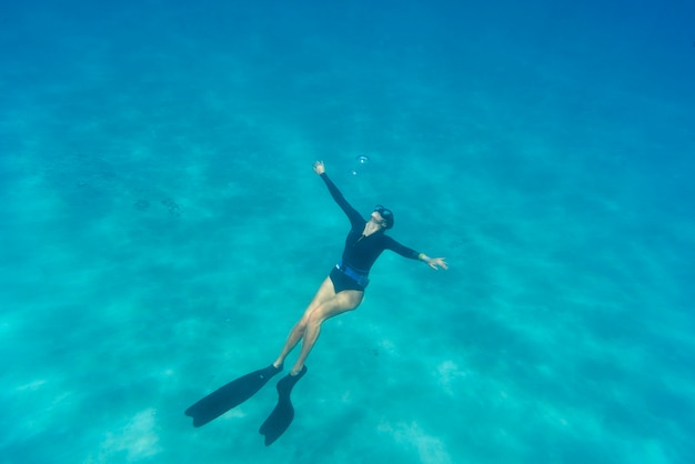 Женщина фридайвинг с ластами под водой