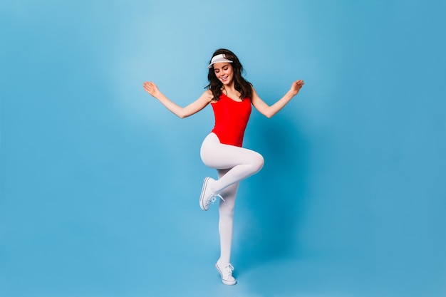 Woman from 80s jumps on blue wall