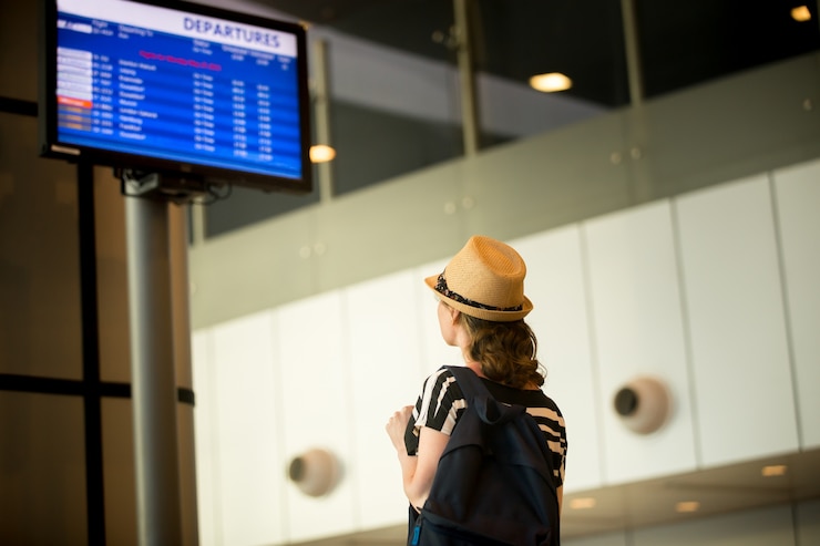 Free Photo woman in front of airport flight information panel