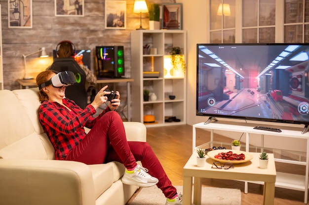 밤늦게 거실에서 VR 헤드셋을 사용하여 비디오 게임을 하는 여성 게이머