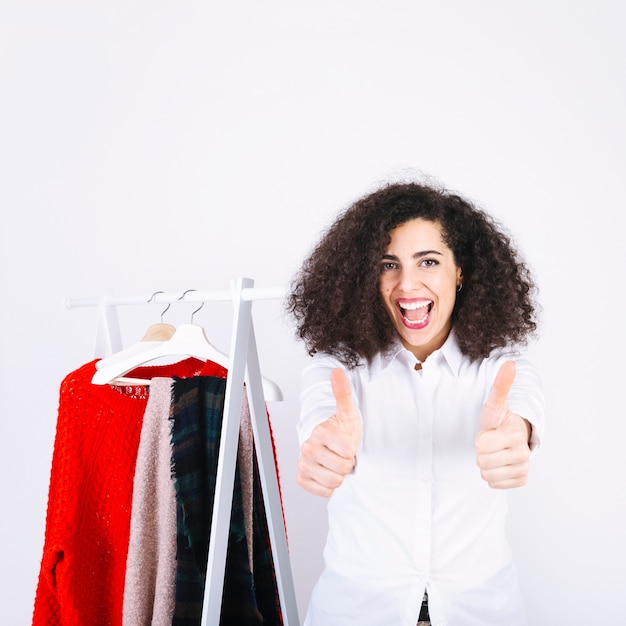 Free photo woman gesturing thumb up near clothes rack