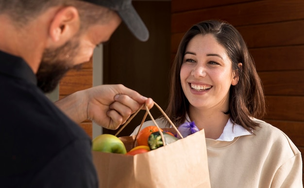 Foto gratuita donna che ottiene un sacchetto di cibo consegnato