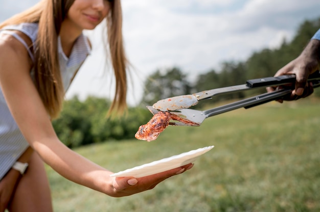 Woman getting grilled meat from the barbecue