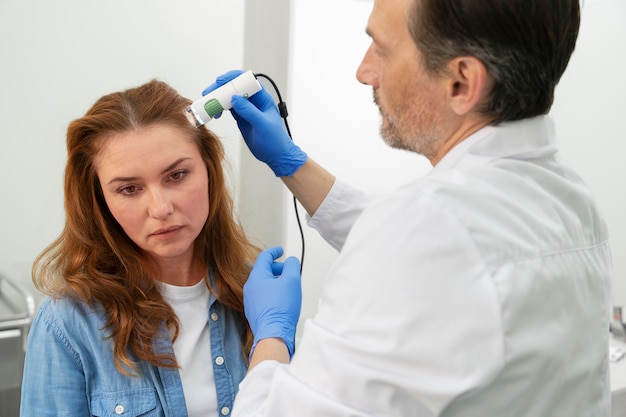 Foto gratuita donna che si sottopone a un trattamento per la caduta dei capelli in una clinica