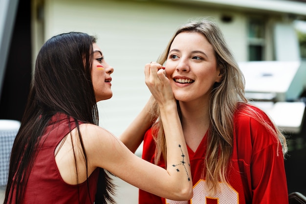 Free photo woman getting her cheeks painted with her team colors