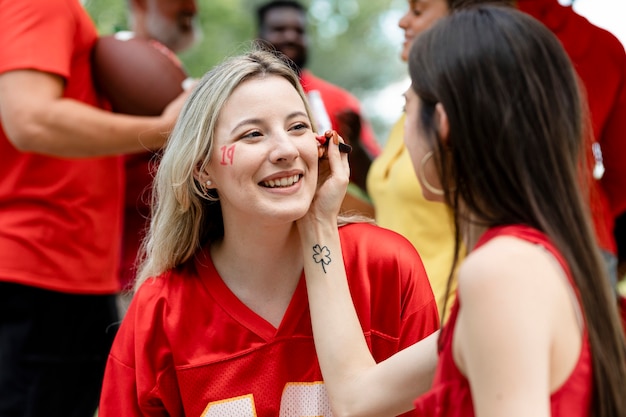 Woman getting her cheeks painted with her team colors