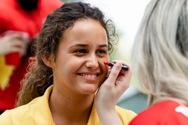 Woman getting her cheeks painted with her team colors