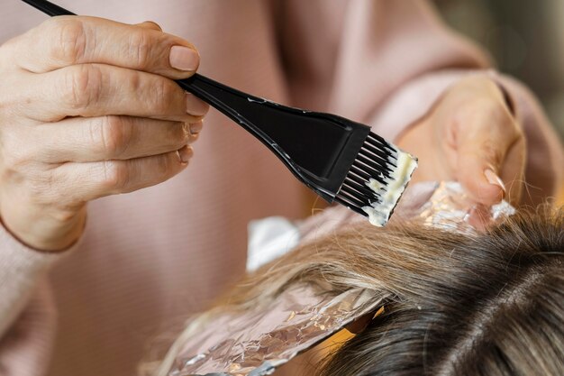 Женщина красит волосы дома косметологом