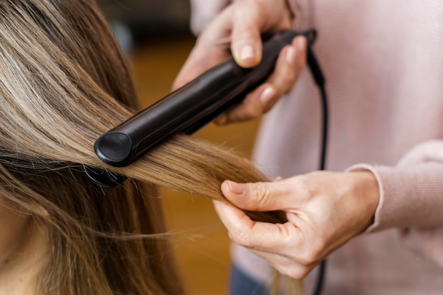 Woman getting her hair straightened at home