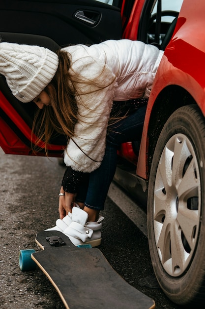 車からスケートボードを取り出している女性