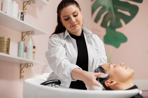 Woman getting treatment at hairdresser shop