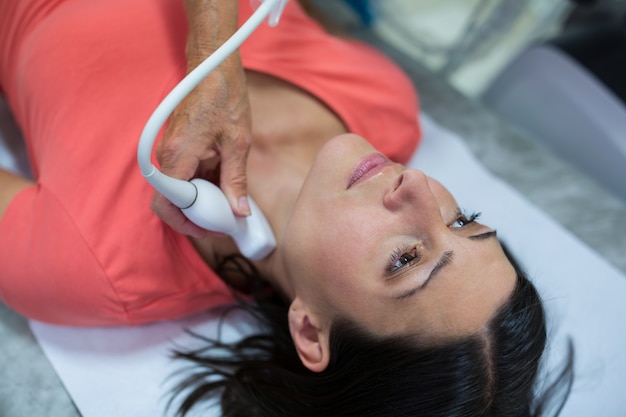 医師から甲状腺の超音波検査を受ける女性