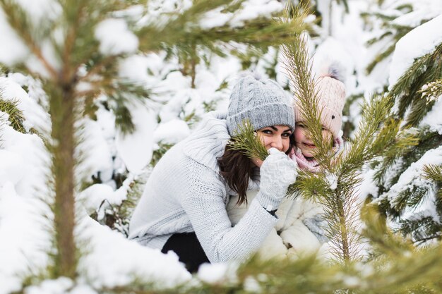 Woman and girl hiding behind spruce