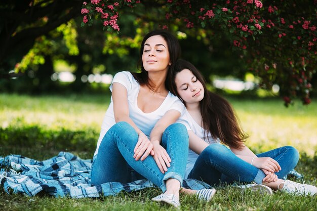 Woman and girl leaning on each other