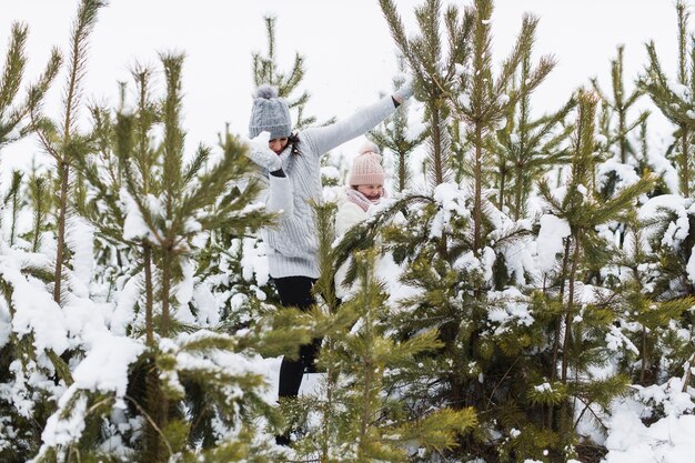 Woman and girl playing near spruces