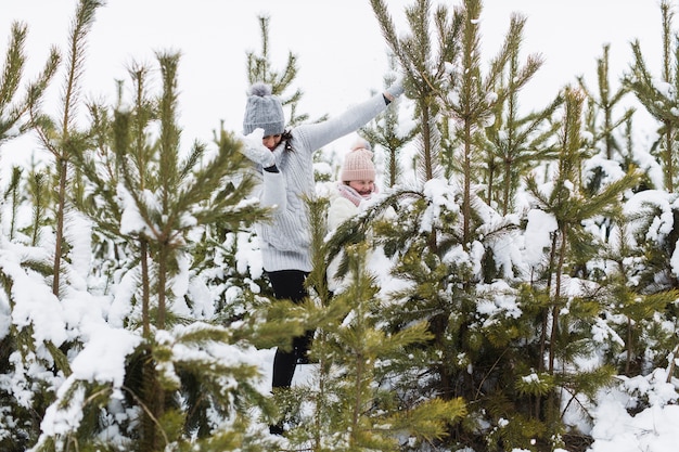 Woman and girl playing near spruces