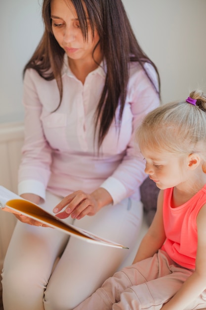 Woman and girl reading book together