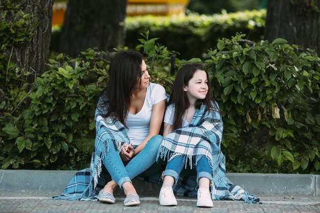 Woman and girl sitting on street curb