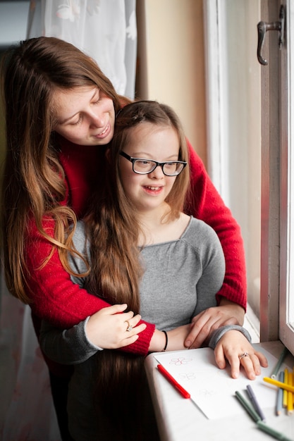 Woman and girl with down syndrome posing by window