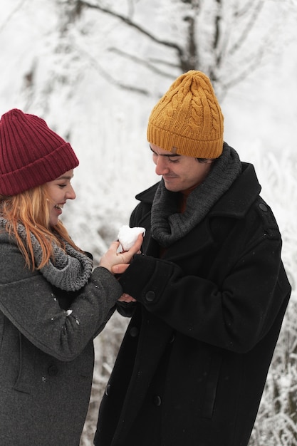 Foto gratuita la donna dà a forma di cuore fatta di neve al suo fidanzato