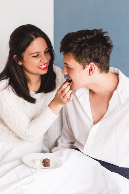 Женщина дает конфету к своему парню в рот