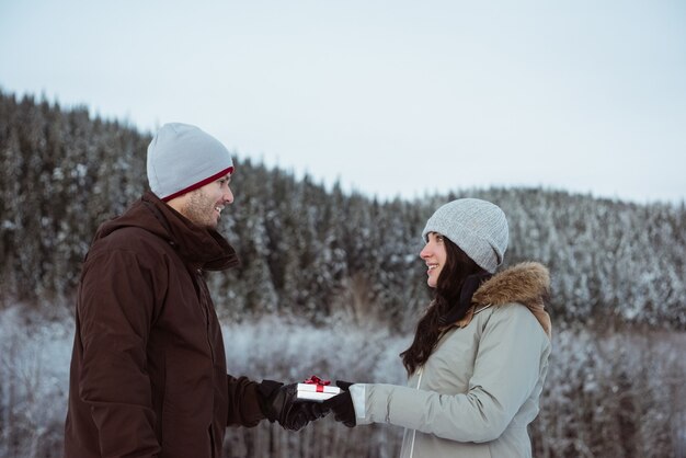 雪に覆われた山で男性に贈り物をする女性