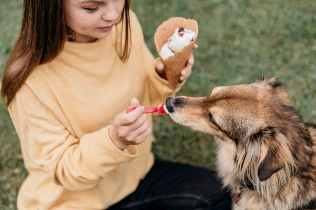 Женщина дает мороженое своей собаке