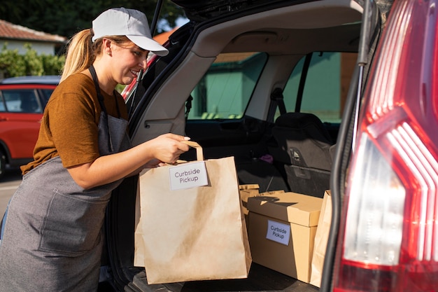 Woman giving an order to a customer at a curbside pickup outside