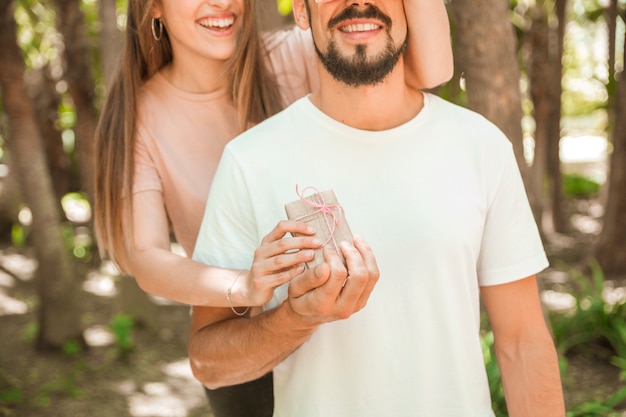 Foto gratuita donna che dà un regalo a sorpresa al suo fidanzato