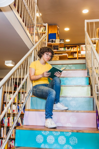 Woman in glasses leaning railings in library