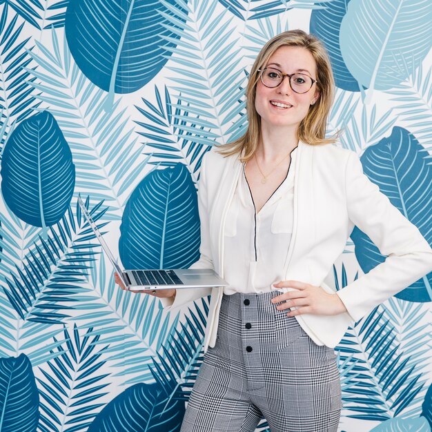 Woman in glasses standing with laptop