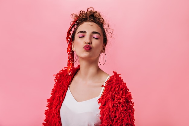 Woman in good mood blowing kiss on pink