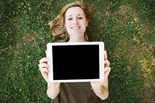 Foto gratuita donna su erba che mostra tablet