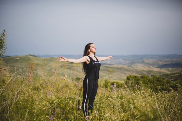 Woman in grass with hands apart