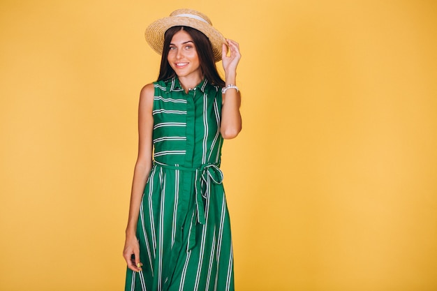 Woman in green dress and hat on yellow background