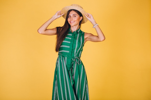 Free photo woman in green dress and hat on yellow background